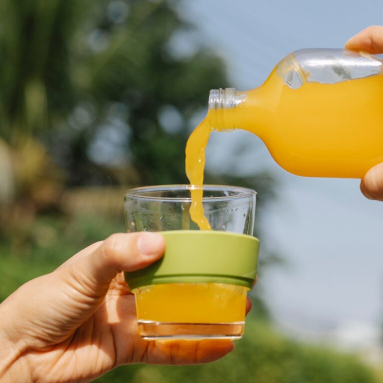 a person pouring orange juice into a glass