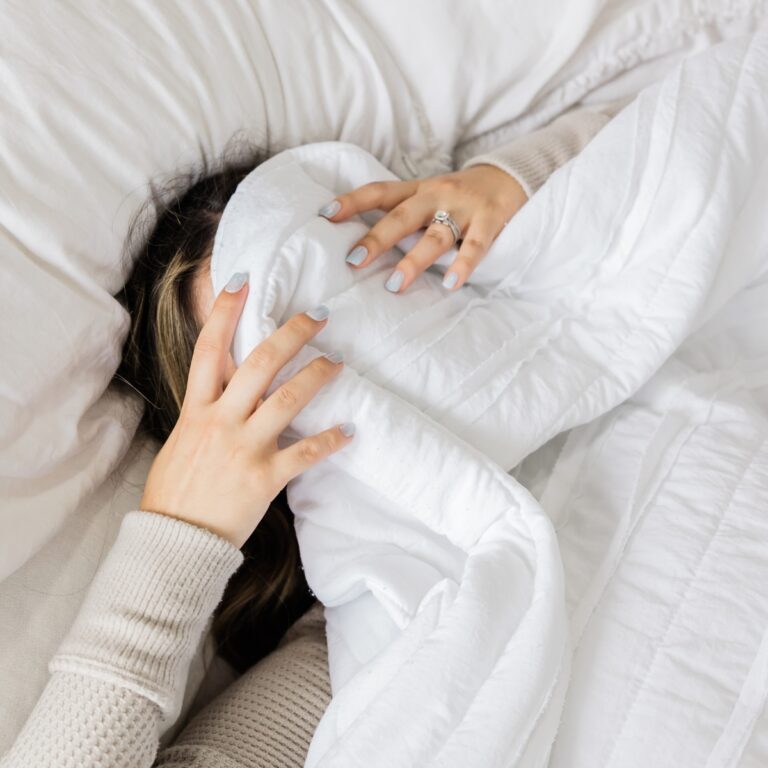 a woman lying in bed with her hand covering her face