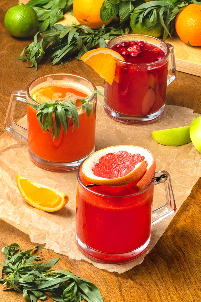 a group of glasses with different colored juice